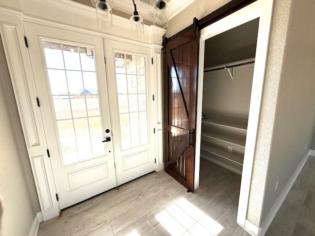 doorway with light wood-style flooring, baseboards, and a barn door