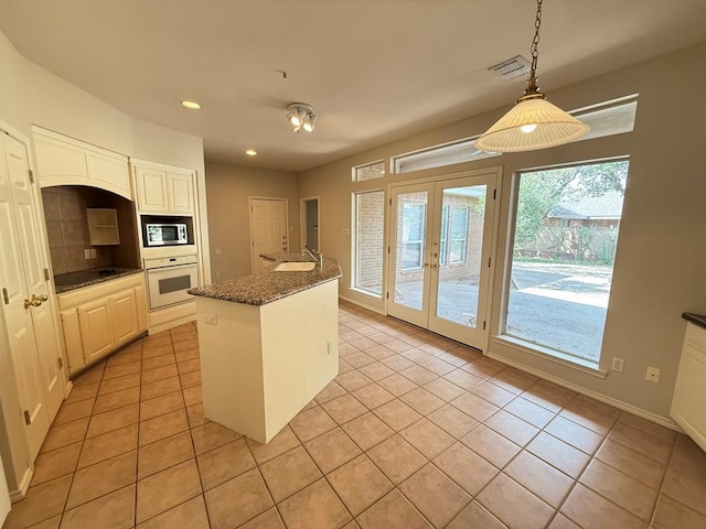 4805 Spring Meadow Ln Unit 6, Midland, TX 79705 - kitchen with oven, stainless steel microwave, light tile patterned flooring, recessed lighting, and hanging light fixtures