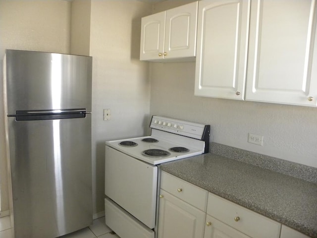 kitchen featuring white cabinetry, stainless steel fridge, light tile patterned floors, and electric range