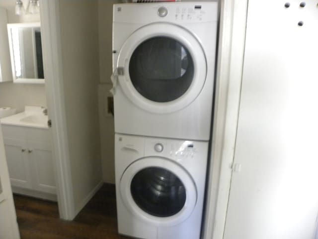 washroom featuring stacked washing maching and dryer and dark wood-type flooring