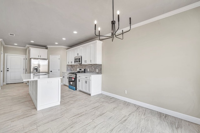 kitchen with sink, an island with sink, decorative backsplash, white cabinets, and appliances with stainless steel finishes