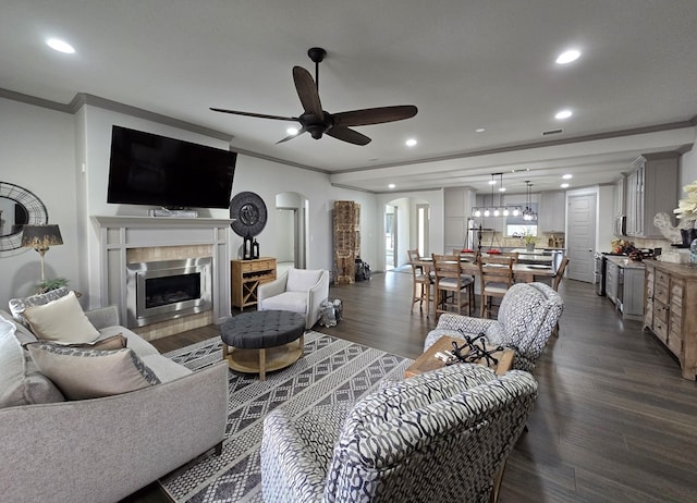 living room with ceiling fan, ornamental molding, a premium fireplace, and dark hardwood / wood-style floors