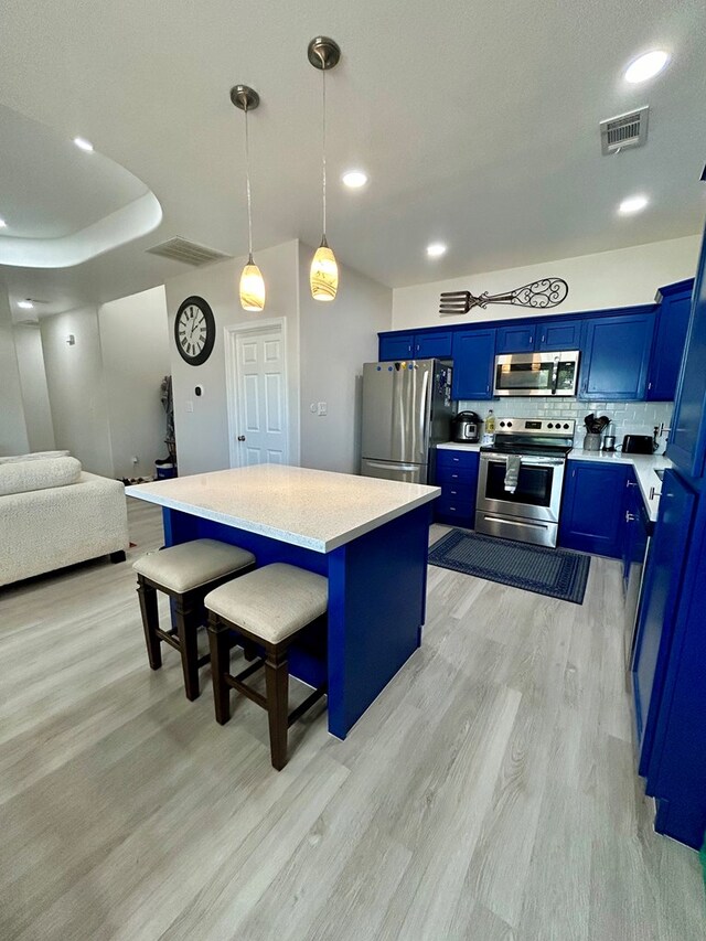 kitchen with a breakfast bar area, blue cabinetry, stainless steel appliances, and light wood-type flooring