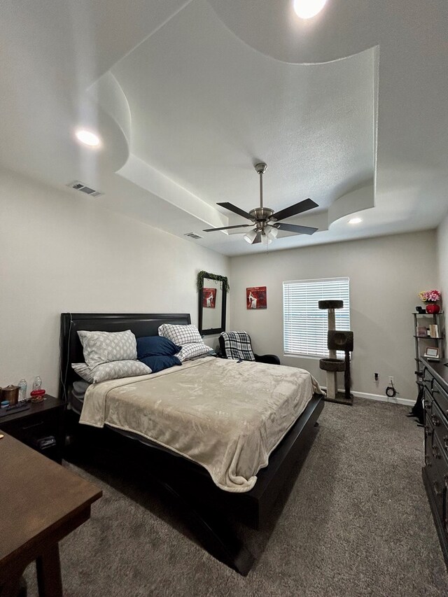 carpeted bedroom with ceiling fan and a raised ceiling