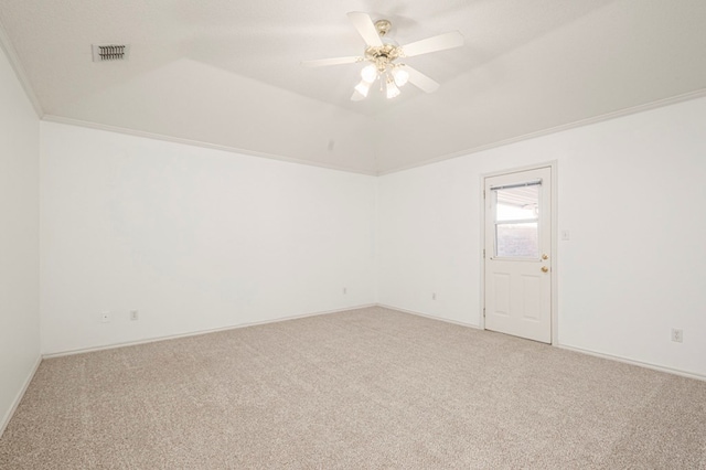 carpeted empty room featuring vaulted ceiling, ornamental molding, visible vents, and a ceiling fan