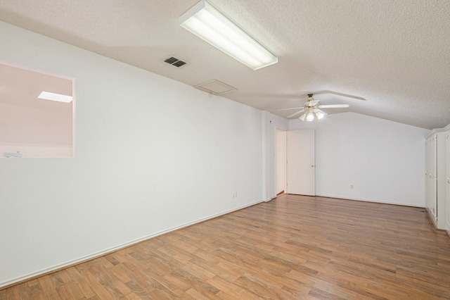 spare room featuring a textured ceiling, light wood-type flooring, visible vents, and a ceiling fan