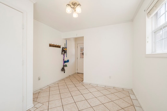 empty room with light tile patterned floors, ornamental molding, and baseboards