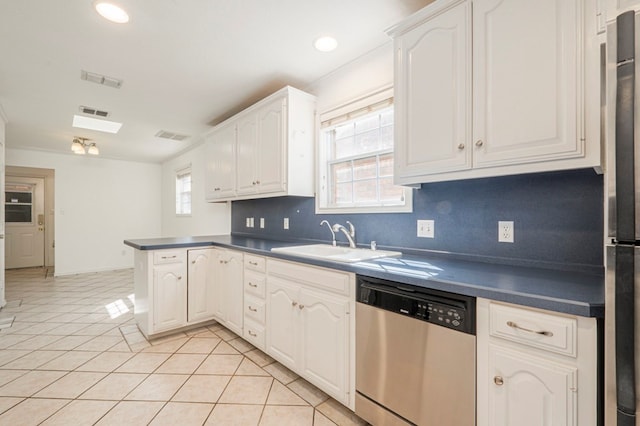 kitchen featuring appliances with stainless steel finishes, dark countertops, white cabinets, and a peninsula