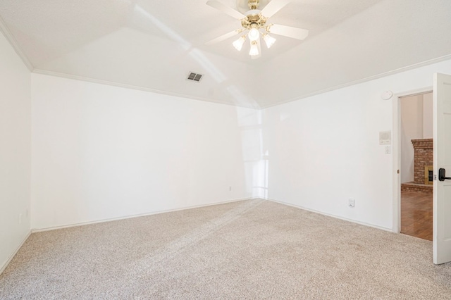 carpeted empty room with ceiling fan, ornamental molding, vaulted ceiling, and visible vents