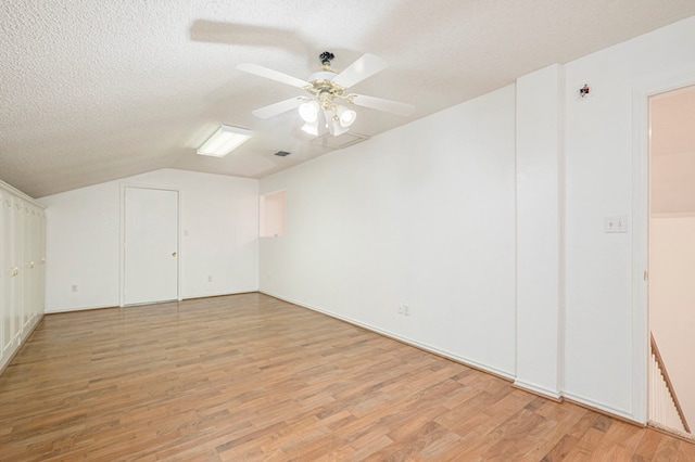 additional living space featuring a textured ceiling, light wood-type flooring, lofted ceiling, and a ceiling fan