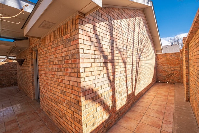 view of side of property featuring brick siding and a patio