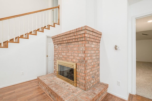 unfurnished living room featuring a brick fireplace and wood finished floors