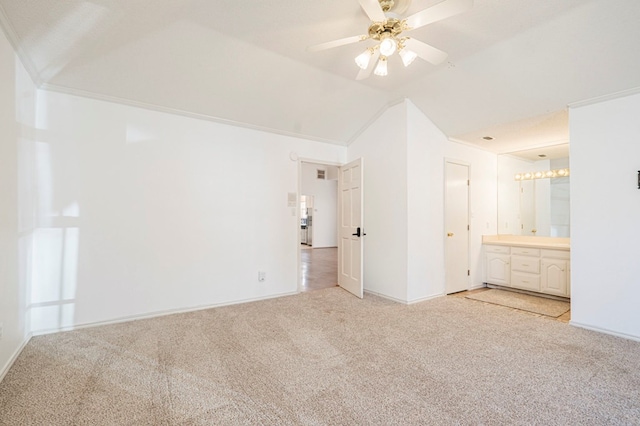 unfurnished bedroom with lofted ceiling, connected bathroom, a ceiling fan, and light colored carpet