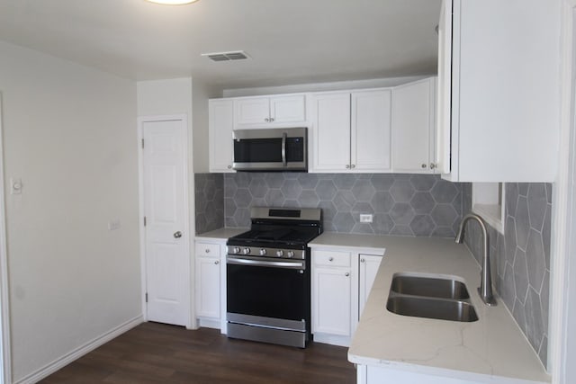 309 W Estes Ave, Midland, TX 79701 - kitchen with stainless steel appliances, dark wood-type flooring, light stone countertops, white cabinets, and tasteful backsplash