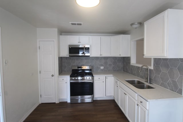 309 W Estes Ave, Midland, TX 79701 - kitchen featuring stainless steel appliances, dark wood-style flooring, backsplash, and white cabinetry