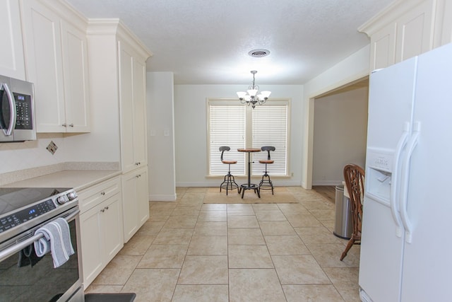 kitchen with white cabinets, light tile patterned floors, appliances with stainless steel finishes, tasteful backsplash, and a chandelier