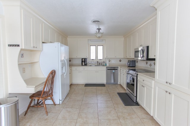 kitchen featuring white cabinetry, sink, decorative backsplash, light tile patterned floors, and appliances with stainless steel finishes