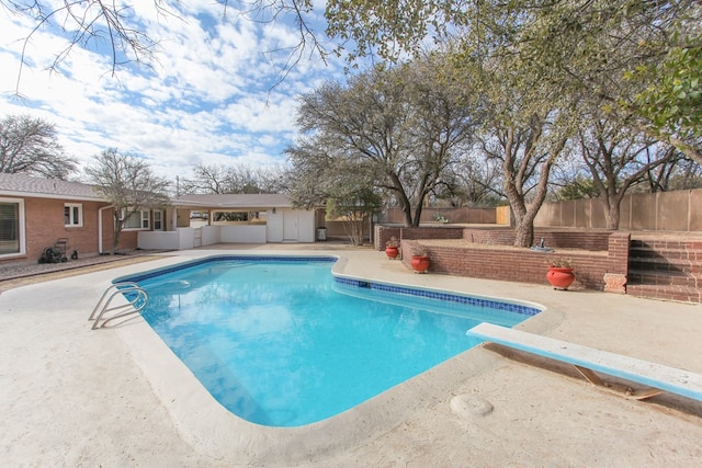 view of swimming pool with a diving board and a patio area