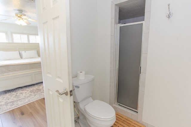 bathroom with wood-type flooring, toilet, ceiling fan, and a shower with shower door