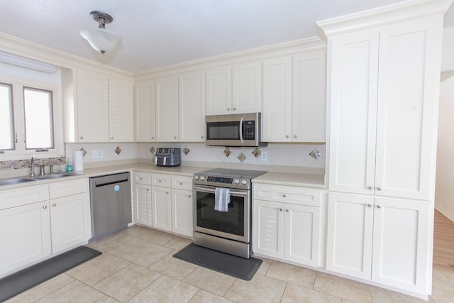 kitchen featuring white cabinets, sink, light tile patterned floors, appliances with stainless steel finishes, and tasteful backsplash