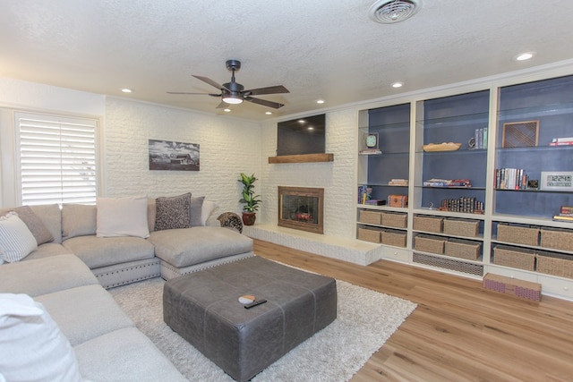 living room with a fireplace, a textured ceiling, hardwood / wood-style flooring, and ceiling fan