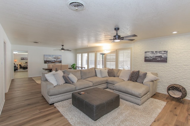 living room with hardwood / wood-style floors, ceiling fan, and a textured ceiling