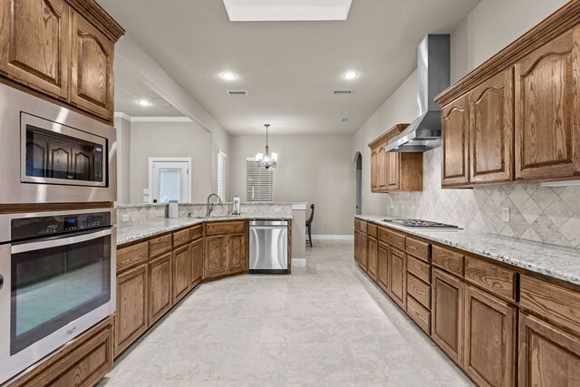 3101 Fairfield Ln, Midland, TX 79705 - kitchen with stainless steel appliances, wall chimney exhaust hood, a chandelier, baseboards, and decorative backsplash