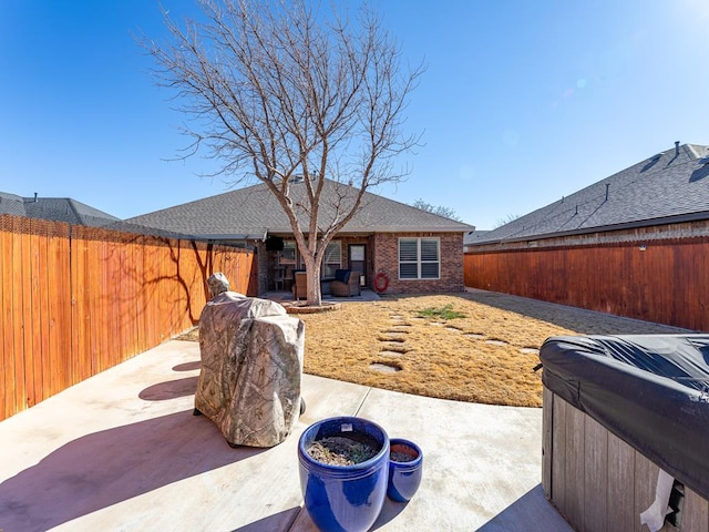 rear view of property with a hot tub and a patio