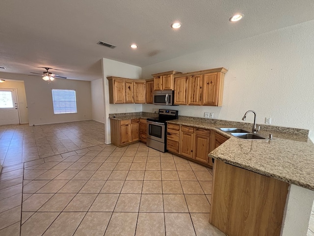kitchen featuring visible vents, a sink, stainless steel appliances, a peninsula, and light tile patterned floors