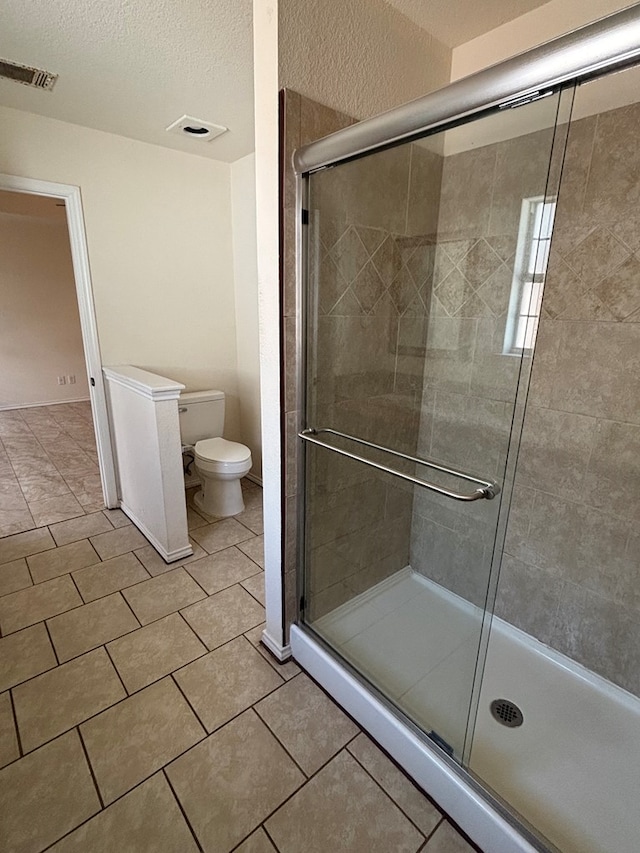 full bath with visible vents, a stall shower, a textured ceiling, tile patterned floors, and toilet