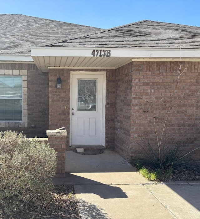 property entrance with brick siding and roof with shingles