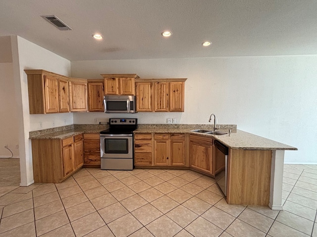 kitchen featuring visible vents, a peninsula, light tile patterned flooring, a sink, and stainless steel appliances