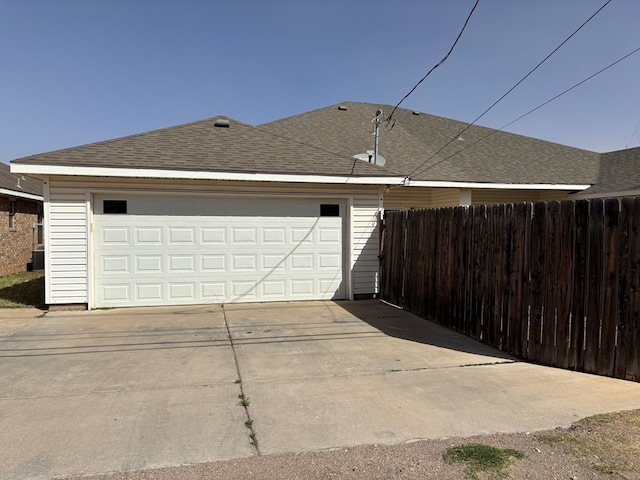 garage with concrete driveway and fence