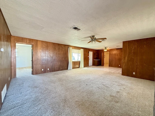 interior space featuring ceiling fan, a textured ceiling, and wooden walls