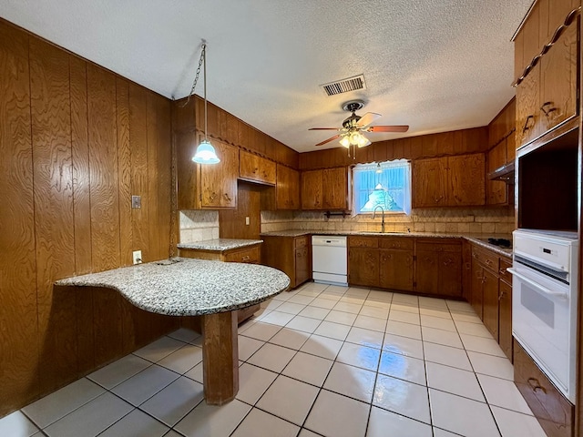 kitchen featuring pendant lighting, a breakfast bar area, ceiling fan, kitchen peninsula, and white appliances