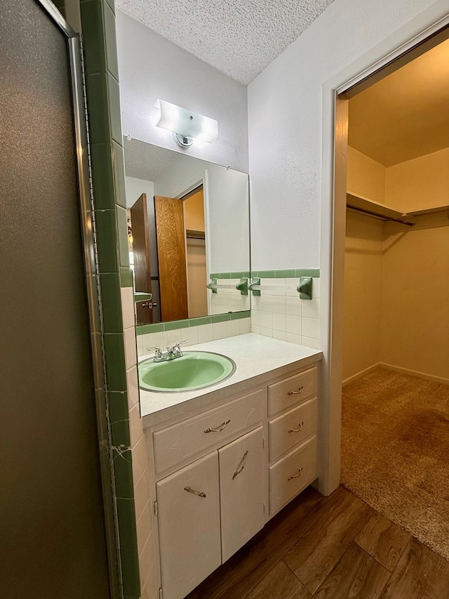 bathroom featuring hardwood / wood-style flooring, vanity, an enclosed shower, and a textured ceiling