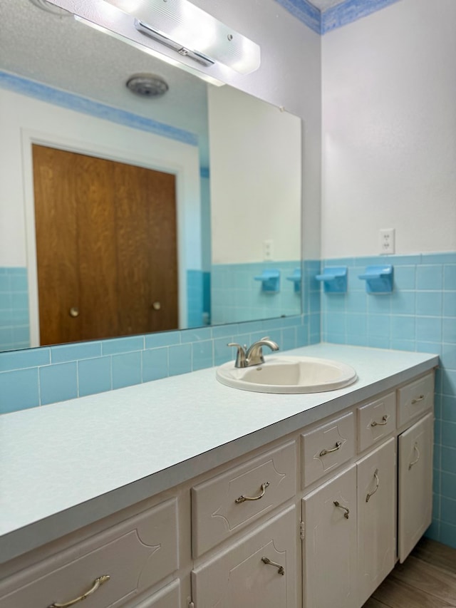 bathroom with vanity, hardwood / wood-style floors, and tile walls