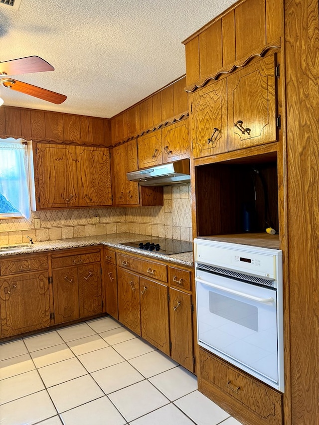 kitchen featuring black electric cooktop, ceiling fan, white oven, and backsplash