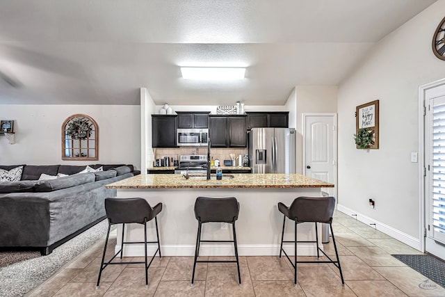 kitchen featuring a breakfast bar area, a healthy amount of sunlight, an island with sink, and stainless steel appliances