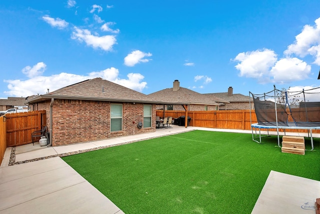 back of house with a yard, a patio, and a trampoline