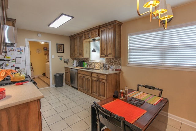 kitchen featuring dishwasher, backsplash, freestanding refrigerator, light countertops, and a sink