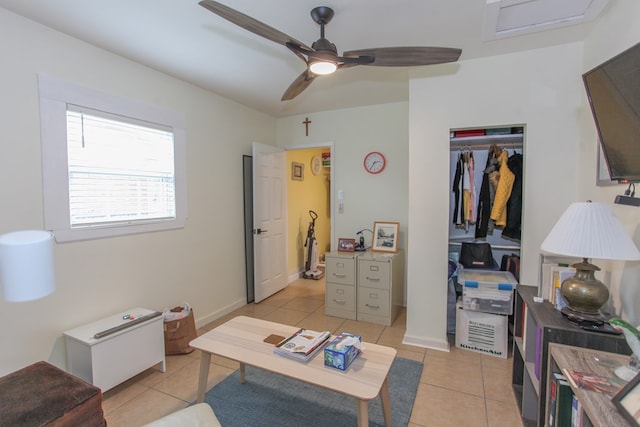 interior space with light tile patterned floors, a ceiling fan, and baseboards