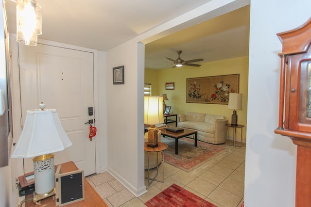 living area featuring a ceiling fan, baseboards, and light tile patterned floors