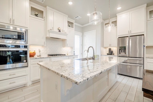 kitchen with pendant lighting, white cabinetry, a center island with sink, and appliances with stainless steel finishes