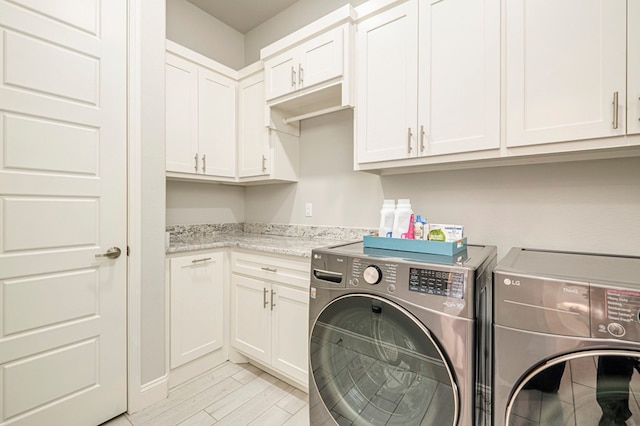 laundry room with cabinets, independent washer and dryer, and light hardwood / wood-style flooring