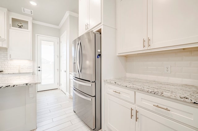 kitchen with white cabinetry, stainless steel fridge with ice dispenser, crown molding, and light stone countertops