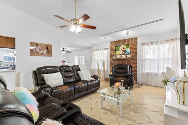 living area featuring a fireplace, a ceiling fan, light tile patterned floors, rail lighting, and vaulted ceiling