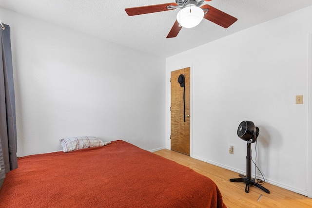 bedroom featuring light wood-type flooring, ceiling fan, and a textured ceiling