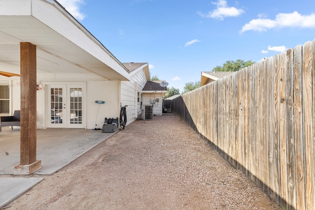 view of yard with french doors, fence, a patio area, and central AC