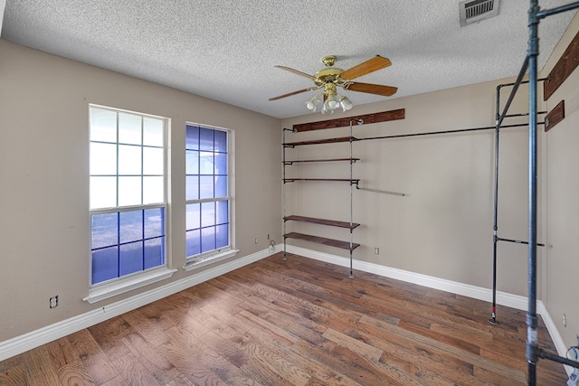 spare room featuring a ceiling fan, visible vents, baseboards, and wood finished floors